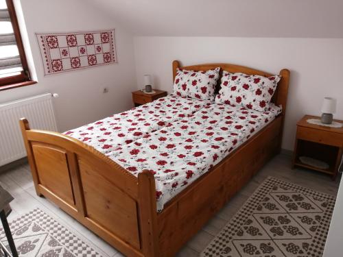 a bedroom with a wooden bed with red flowers on it at Kalotaszeg Vendégház in Izvoru Crişului