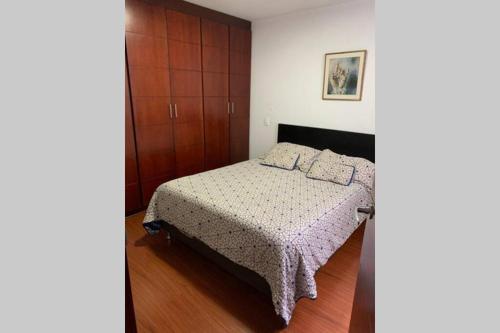 a bedroom with a bed and wooden cabinets at Palermo, Acogedor apartamento en Zona Rosa in Manizales