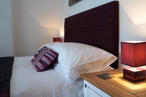 a bedroom with a bed with a wooden headboard and a table at Links Side Guest House in Bude