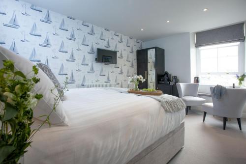 a white bedroom with a large white bed and chairs at Leader, Maritime Suites, Brixham in Brixham