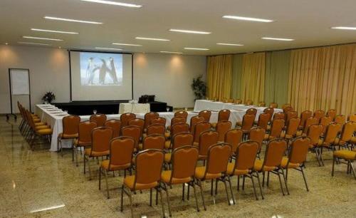 une salle de conférence avec une table, des chaises et un écran dans l'établissement 712 - FLAT para temporada Bristtol Evidence Hotel, à Goiânia