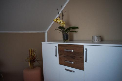 a white cabinet with a vase of flowers on it at Golden BIS, Subotica in Subotica