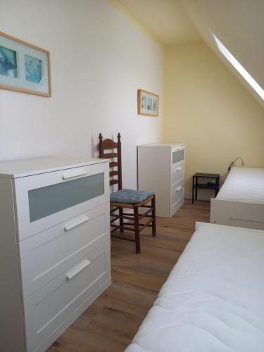 a bedroom with a bed and a dresser and a chair at Schooster Huus in Nordstrand