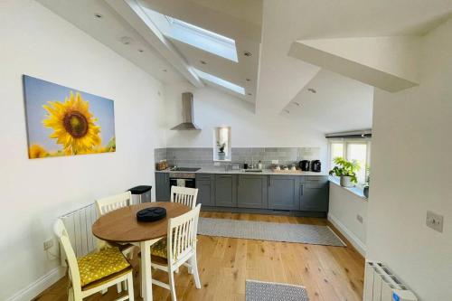 a kitchen with a table and a kitchen with a sunflower painting at Paddock View, Castle Combe in Castle Combe