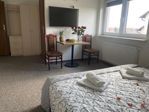 a bedroom with a bed and a table and a tv at Hotelik Gold in Raszyn