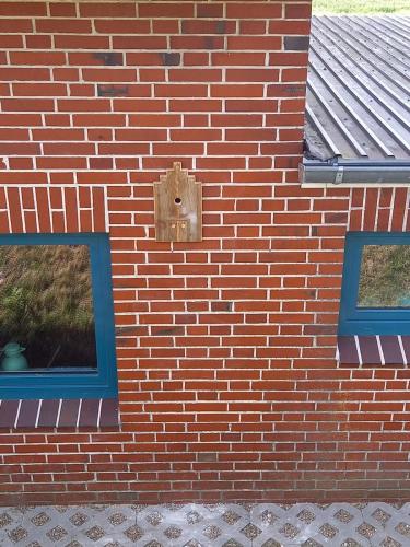 a brick wall with two windows and a socket at Schooster Huus in Nordstrand