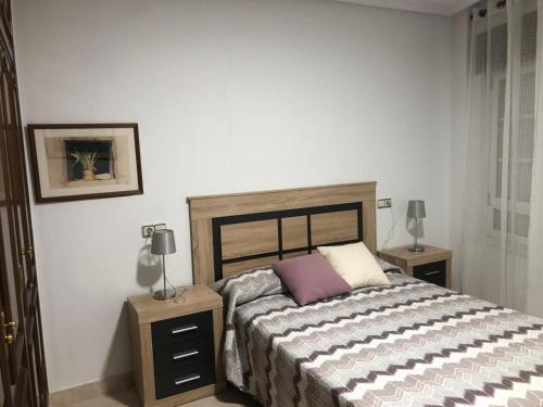 een slaapkamer met een bed met 2 nachtkastjes en 2 lampen bij LA CASA DEL ESTANCO in Fermoselle