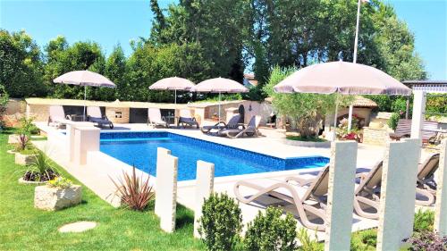 a pool with chairs and umbrellas in a yard at Apartment Villa Engel with Pool in Poreč