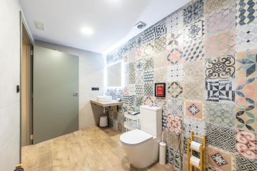 a bathroom with a toilet and a tile wall at ART LOFTS Valencia by Benisur in Valencia