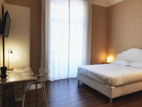 a bedroom with a bed and a desk and a window at Palazzo La Piana Rooms in Catania