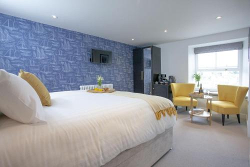 a bedroom with a large white bed and yellow chairs at Vigilance, Maritime Suites, Brixham in Brixham