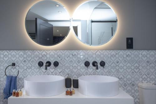 a bathroom with two sinks and two mirrors at Vigilance, Maritime Suites, Brixham in Brixham
