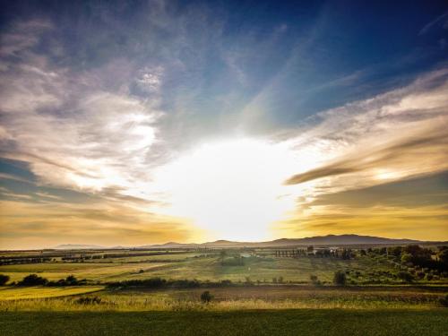 a sunset over a field with the sun in the sky at Il Poggio di Musignano in Musignano