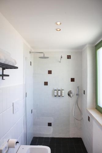 a white bathroom with a shower and a sink at Il Poggio di Musignano in Musignano