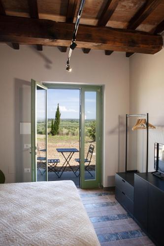 a bedroom with a bed and a patio with a table at Il Poggio di Musignano in Musignano