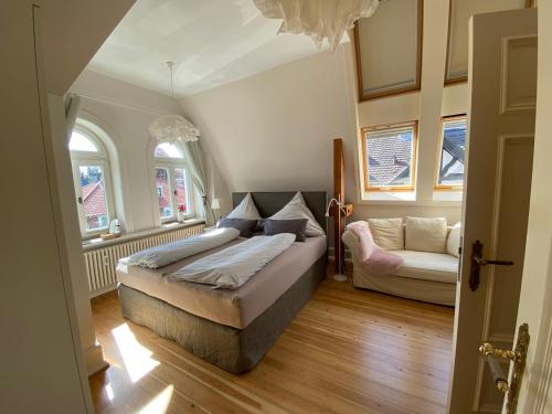 a bedroom with a bed and a couch and two windows at Ferienwohnung Bamberger in Lübeck