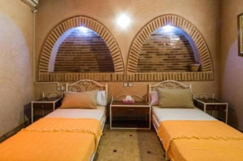 two beds in a room with two arched windows at Villa privée Wafa in Marrakesh
