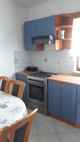uma cozinha com armários azuis, um fogão e uma mesa em Apartment Lara em Medulin