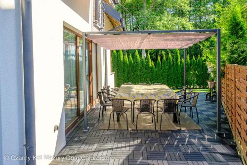 a patio with a table and chairs on a deck at Czarny Kot Mazury Dom Całoroczny in Małkinie