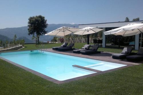 a large swimming pool with chairs and umbrellas at Casa de Louredo-Gerês in Vieira do Minho