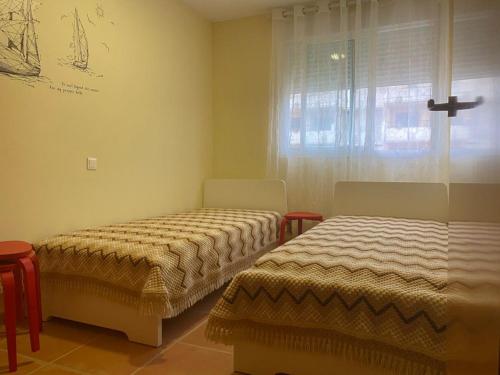 um quarto com 2 camas e uma janela com uma cruz na parede em Nova Almenara. Ideal para familias em Barrio-Mar