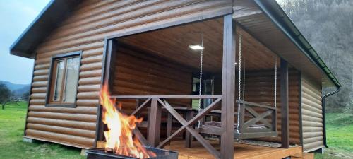a log cabin with a fire in front of it at Оберіг in Sheshory