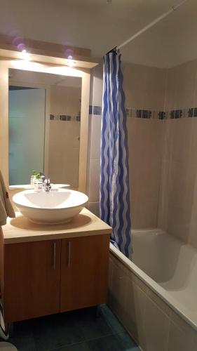 a bathroom with a sink and a tub and a mirror at Appartement 2 chambres avec jardinet, piscine vue sur la montagne in Luz-Saint-Sauveur