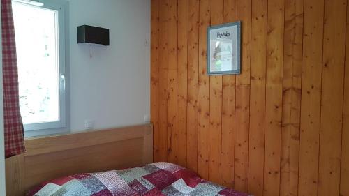 a bedroom with a wooden wall with a bed and a window at Appartement 2 chambres avec jardinet, piscine vue sur la montagne in Luz-Saint-Sauveur