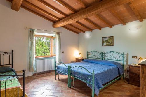 Un dormitorio con una cama azul y una ventana. en Agriturismo Casa al Bosco, en Volterra