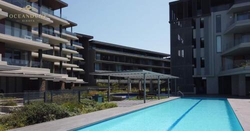 una piscina con sombrillas frente a un edificio en 254 Ocean Dune Sibaya, en Umhlanga