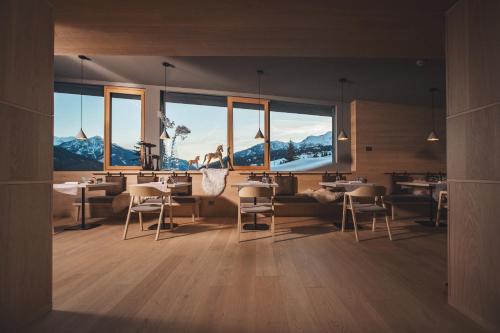 a restaurant with tables and chairs and large windows at Olympic SPA Hotel - Adults Only in Vigo di Fassa