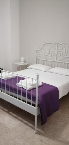 a white bed with a purple blanket on it at Sant'Ermete in Matino