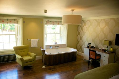 a bathroom with a tub and a chair and a bed at The Oaksmere in Eye