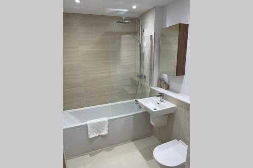 a bathroom with a sink and a toilet and a tub at Croydon Gem Apartment - Fast train to the centre and free parking in Purley