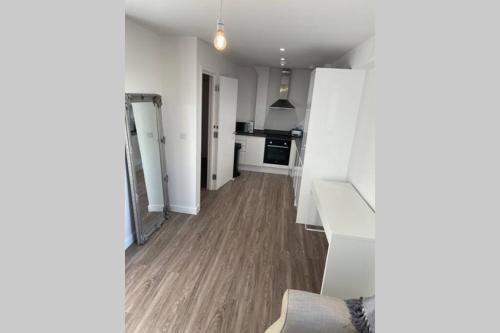 a kitchen with white walls and a wooden floor at Croydon Gem Apartment - Fast train to the centre and free parking in Purley