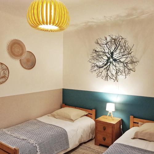 une chambre avec deux lits et un lustre dans l'établissement Appartement T2bis Sartène 60m2 avec jolie terrasse de 25m2 et vue panoramique mer et montagne sur le Golfe du Valinco - Quartier calme à 10mn à pied du centre ville - Idéal pour 4 personnes et possibilité de 6 couchages - Place de parking réservée, à Sartène