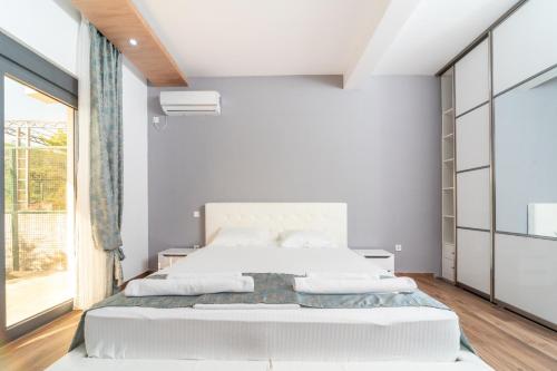 a white bedroom with a large bed and a window at Resort Bevilacqua in Budva