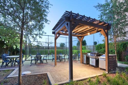 a wooden pergola with a grill and tables and chairs at Staybridge Suites Plano - Richardson Area by IHG in Plano