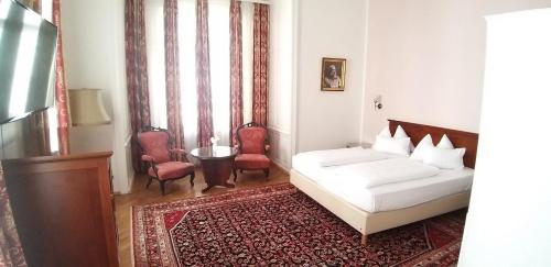 
a hotel room with two beds and a chair at Hotel Domizil in Vienna
