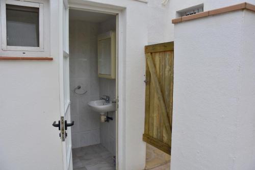 a bathroom with a sink and a wooden door at Casa Daguet in L'Eucaliptus