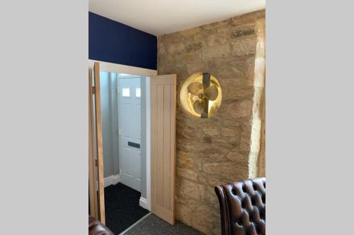 a room with a chair and a stone wall at The Rockpool - private hot tub and sea views in Amble