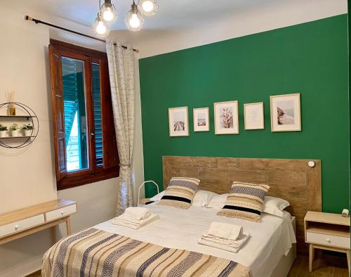 1 dormitorio con 1 cama con pared verde en Dimora Dionisio B&B, en Florencia