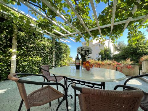 einen Tisch und Stühle unter einer Pergola mit einer Flasche Wein in der Unterkunft Villa Mila in Petrovac na Moru