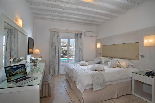 a bedroom with a bed and a laptop on a desk at Dionysos Luxury Hotel Mykonos in Ornos