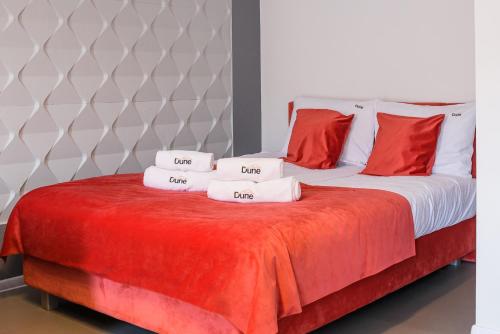 a bed with red and white pillows on it at Pokoje, Noclegi, Apartamenty Dune Resort Łeba in Łeba