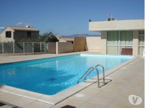 une piscine avec de l'eau bleue devant un immeuble dans l'établissement mini-villa, à Grosseto-Prugna