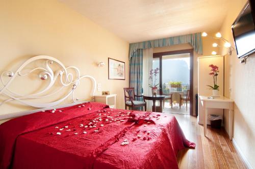 a bedroom with a red bed with a redspread at Villa Madrina Lovely and Dynamic Hotel in Garda