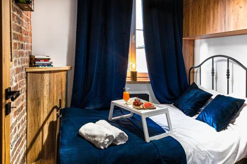 a bed with blue pillows and a table on it at Heart of the Old WROCLOVE in Wrocław