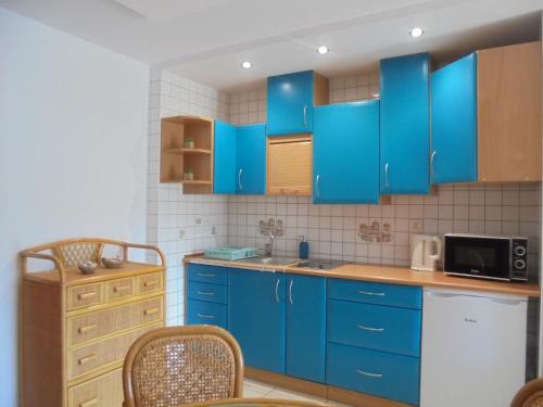 a blue kitchen with blue cabinets and a microwave at Apartament dwupokojowy 150 m do morza in Jarosławiec