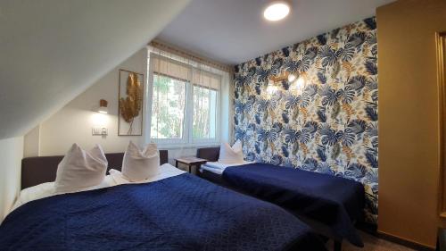 1 dormitorio con 2 camas y papel pintado azul y blanco en Zajazd GNIEWKO en Mała Karczma